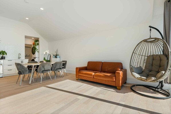 A modern living room with a sofa, dining table, chairs, and a hanging chair. - Beautiful lakeside beach front cottage (FREE PONTOON/SEADOO RENTAL INCLUDED) (Vittoria)