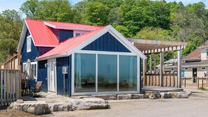 Un bâtiment bleu avec un toit rouge, une structure en verre et une terrasse en bois.