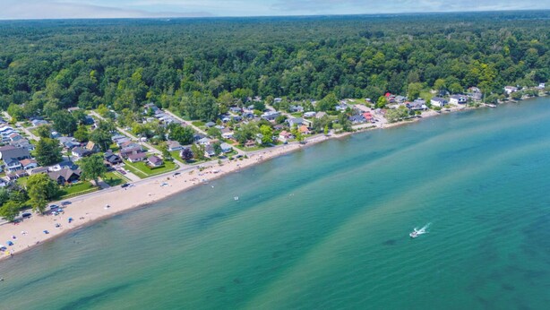 Vue aérienne d’une zone résidentielle côtière, avec des maisons, une plage et une étendue d’eau.