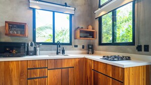 Une cuisine moderne avec des meubles en bois, une cuisinière à gaz, un four à micro-ondes et une machine à café.