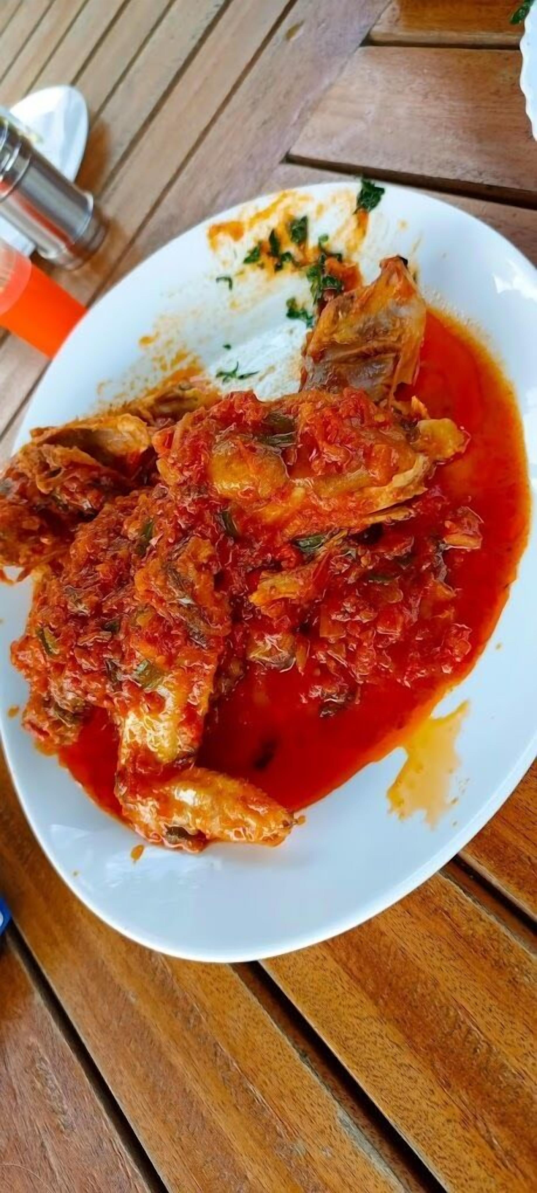 A plate of fish with a red sauce, served on a white plate.