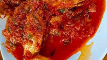 A plate of fish with a red sauce, served on a white plate.