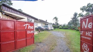 A gated entrance with red metal gates labeled "The Guest House." - The Nest Guest House Kericho (Kericho)