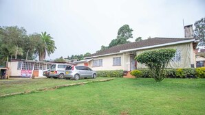 A residential house with a lawn, a parked car, and a small garden area. - The Nest Guest House Kericho (Kericho)