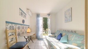 A room with a bed, a chair, a table, and a window.