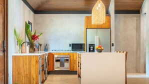 Une cuisine moderne avec des meubles en bois, un îlot central, un four à micro-ondes et un réfrigérateur.