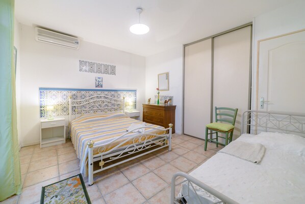 Une chambre à coucher comprenant un lit, une chaise, une table de chevet, une commode et une armoire.