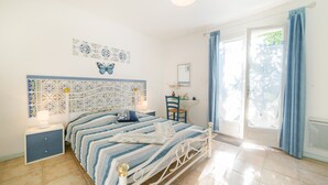 A bedroom with a bed, nightstands, a chair, a window with curtains, and a wall with a butterfly decoration.