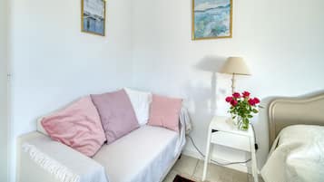 Una stanza con un letto, un comodino con una lampada, un vaso con fiori e due quadri appesi al muro.