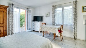 A bedroom with a bed, a TV, a table, and a chair.