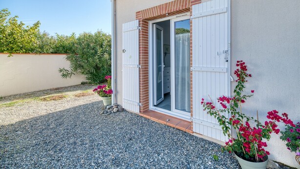 A building with a door, a window, and a gravel driveway.