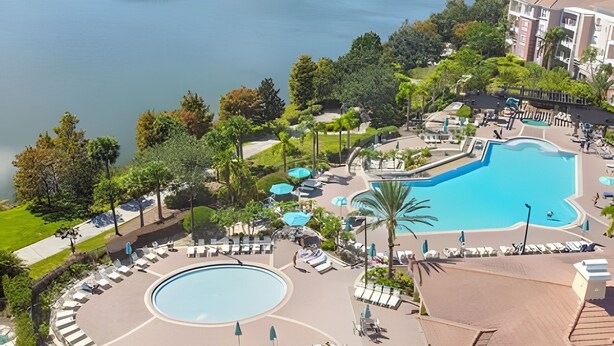 Ein Resort mit einem großen zentralen Pool, einem kleineren kreisförmigen Pool und einem angelegten Bereich mit Liegestühlen und Sonnenschirmen.