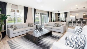 Un salon moderne avec deux canapés, une table basse et, au fond, un espace cuisine.
