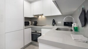 A modern kitchen with white cabinetry, a stainless steel sink, a microwave, a coffee maker, and a kettle. - Apartment 'Eanes 22 Beach House' with Balcony, Wi-Fi and Air Conditioning (Monte Gordo)