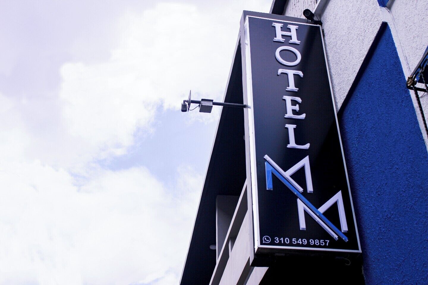 A hotel sign with the name 'HOTEL M' and a phone number.