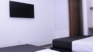 A hotel room with two beds, a flat-screen TV mounted on the wall, and a wooden door. - Ayenda Hotel MM (Pereira)