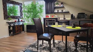 A modern kitchen with dark cabinetry, a dining area with a black table and chairs, and a large window with a view of greenery. - Beautiful LOFT SUITE, Private Guest House located in Hamlet of Mirror. (Mirror)