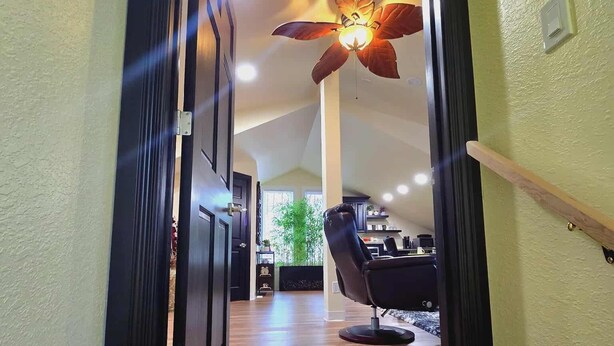 A hallway with a wooden floor leading to a room with a ceiling fan and a chair. - Beautiful LOFT SUITE, Private Guest House located in Hamlet of Mirror. (Mirror)