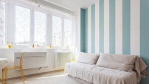 A room with a bed, a chair, a radiator, and large windows. - Riva Reno Apartment (Bologna)