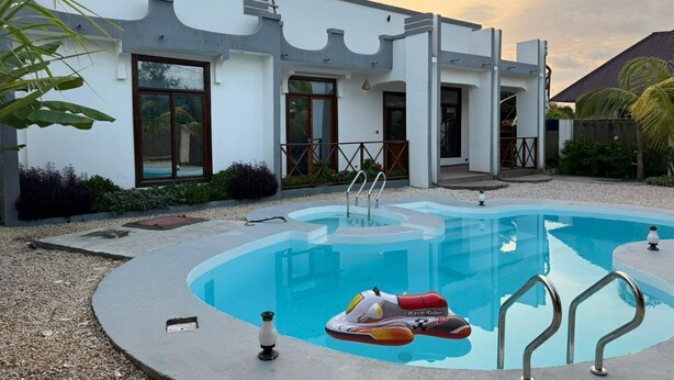 Une maison moderne dotée d’une piscine, d’un flotteur pour faire des vagues et d’une échelle permettant d’y accéder.
