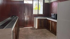 Une cuisine de taille réduite, équipée d’un four à micro-ondes, d’un évier et d’une petite fenêtre.