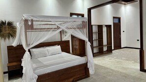 A bedroom with a wooden bed, white bedding, and a canopy. There is a wooden wardrobe and a door in the background. - 3-bedroom villa in charming Zanzibar with Swimming Pool and aircondition (Kiwengwa)