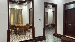 A hallway with a wooden table and chairs, a ceiling fan, and a door with a mirror. - 3-bedroom villa in charming Zanzibar with Swimming Pool and aircondition (Kiwengwa)