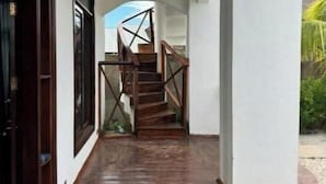 Un couloir au plancher de bois menant à un escalier doté d’une rampe en métal.