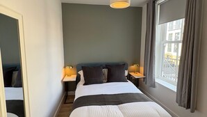 A modern bedroom with a large bed, bedside lamps, a ceiling light, and a window with curtains. - 2 x bed city apartment with parking  (Hull)