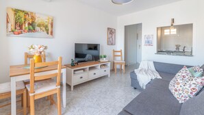 Un salon avec un téléviseur, des meubles en bois, un canapé et un tableau accroché au mur.