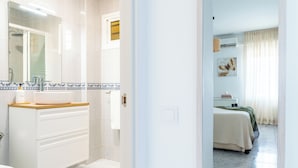 Une salle de bain avec un lavabo blanc, un miroir et un sol carrelé.