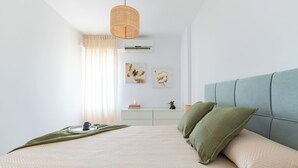 Une chambre à coucher avec un lit, une table de chevet, une lampe et des œuvres d’art murales.