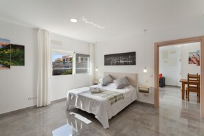 A modern bedroom with a bed, a cityscape view, and a dining area.