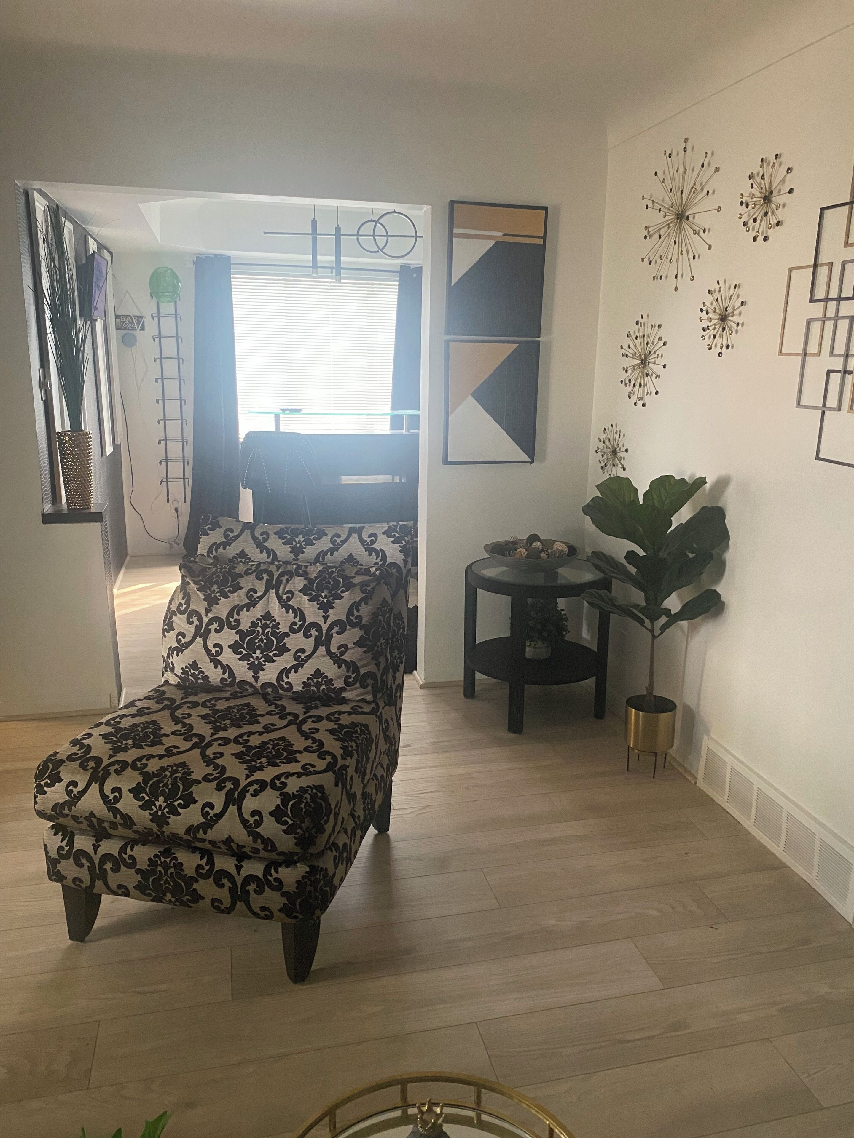 A living room with a patterned sofa, a small round table, and decorative wall art.