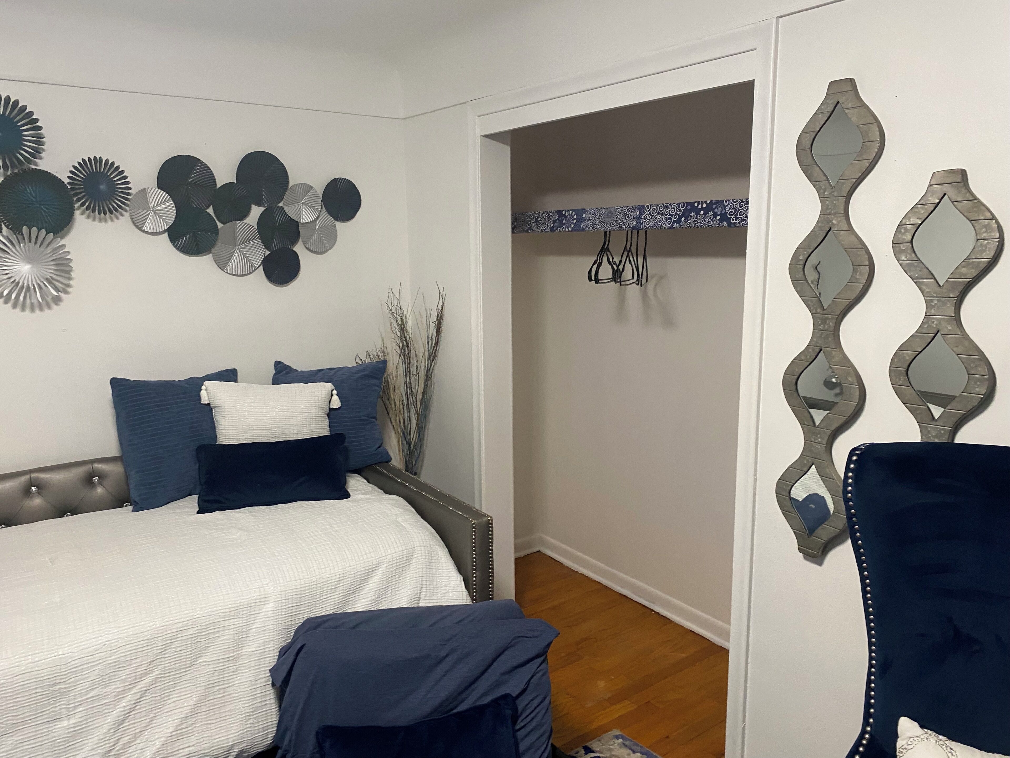 Een slaapkamer met een bed, kussens en decoratieve muurkunst.