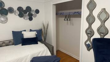 Een slaapkamer met een bed, kussens en decoratieve muurkunst.
