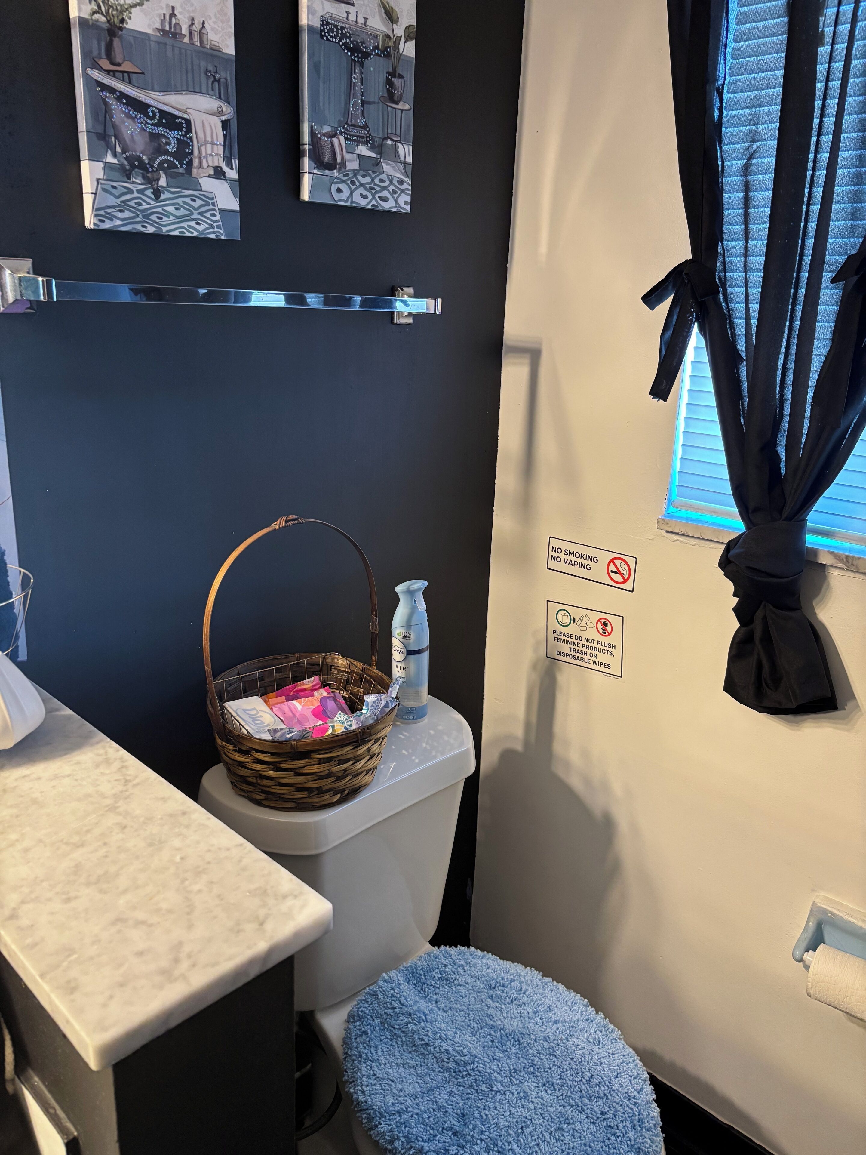 Une salle de bain équipée de toilettes, d’un panier contenant des articles de toilette, d’une serviette et d’un panneau indiquant qu’il est interdit de fumer.