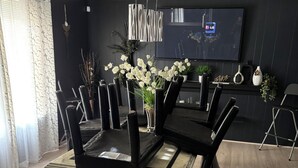 A modern dining area with a marble-top table, black chairs, and a vase of white flowers. - Sunburst Palace Spacious 4-bedrooms a Den-Fulton with AC in Center Line, MI. (Center Line)