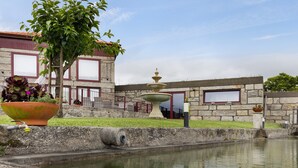 A courtyard with a fountain, a large planter, and a building with stone walls and windows. - Holiday Home 'Lagar T1' with Lake View, Wi-Fi & Air Conditioning (Vieira do Minho)