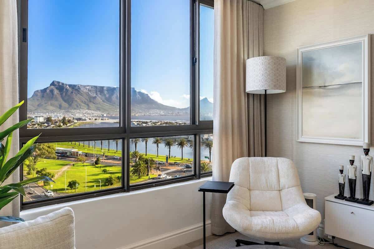 A hotel room with a large window offering a view of a mountain and cityscape.