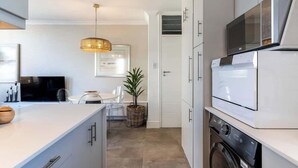Een moderne keuken met witte kastjes, een ingebouwde magnetron en een wasmachine.