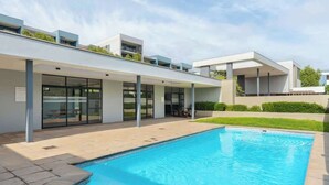 A modern building with a swimming pool, large windows, and a flat roof.