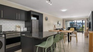 A modern kitchen with dark cabinets, a central island, and a dining area with a view.