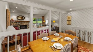 A dining area with a wooden table set for four, surrounded by checkered upholstered chairs. - Fairway Haven with Private hot tub! Dog Friendly! (Sun Valley)