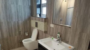 A bathroom with a toilet, sink, and mirror. - Aaron Residency  (New Delhi)