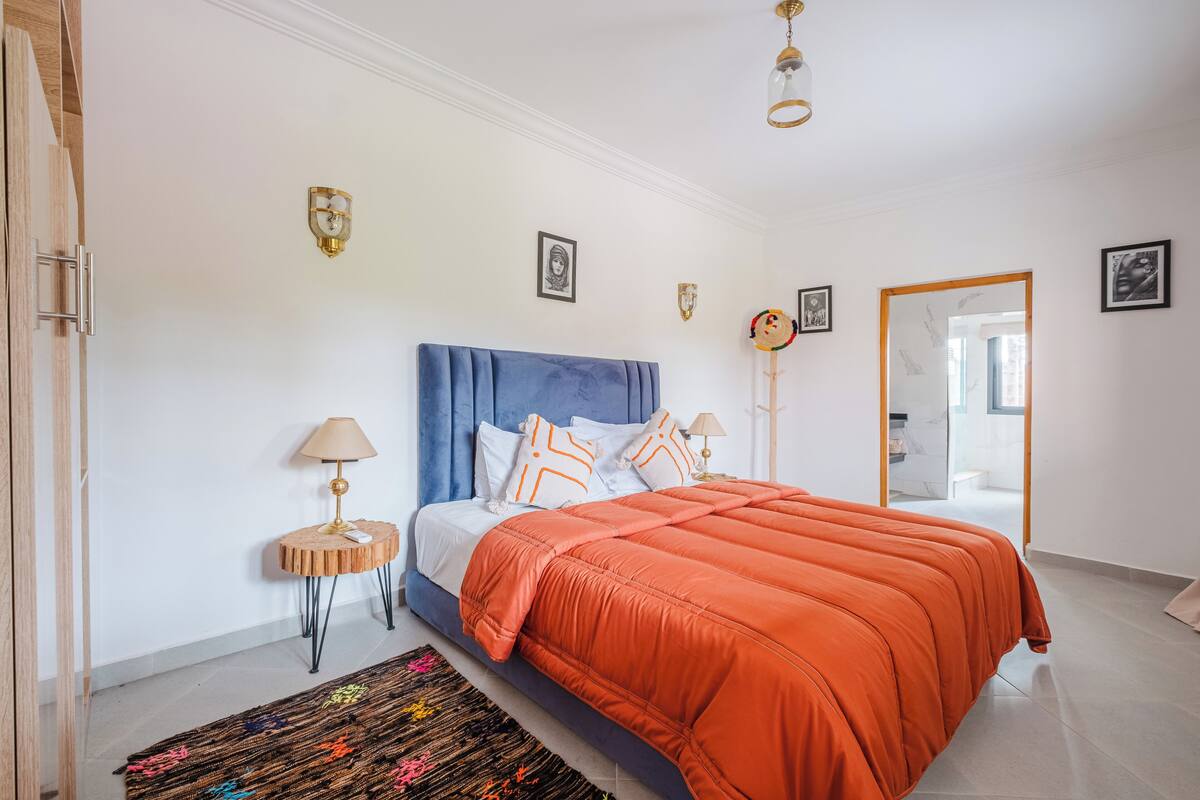 Une chambre à coucher avec un grand lit, une table de chevet, une lampe et un miroir.
