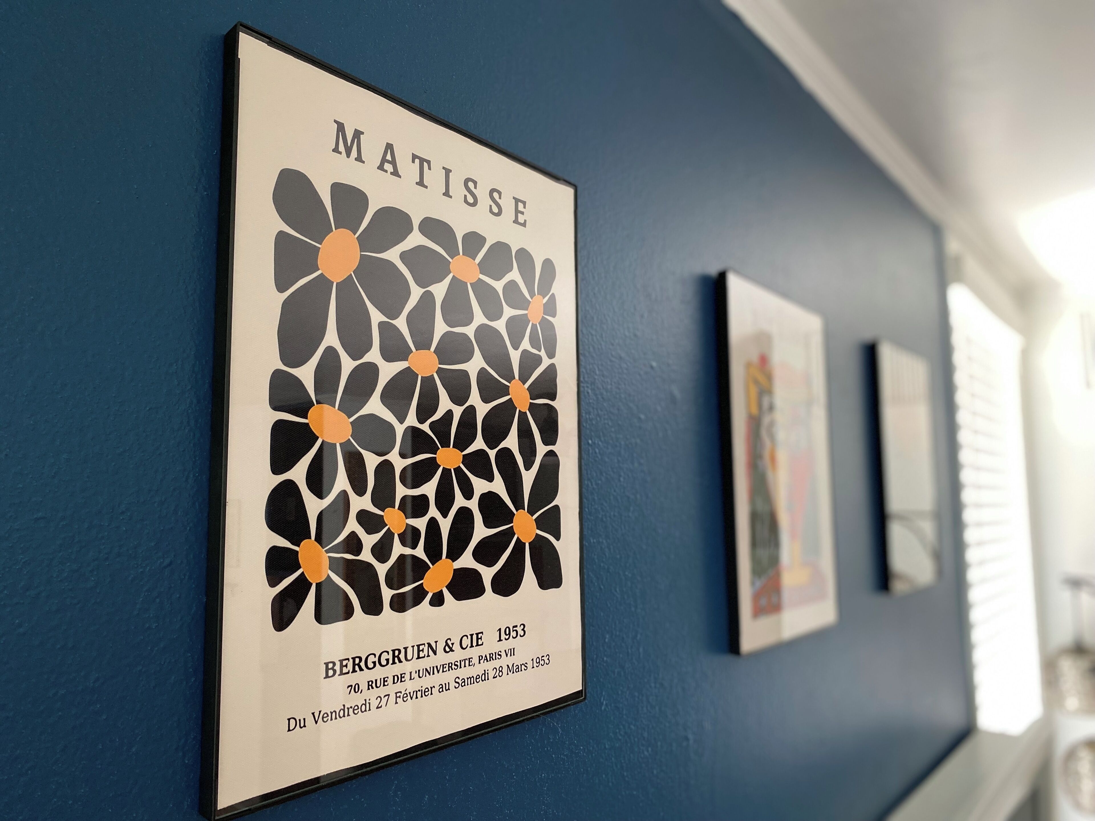 Una obra enmarcada titulada 'MATISSE' de Berggruen & Cie de 1953, expuesta en una pared azul.