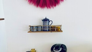 A kitchenette with a coffee maker, a kettle, and a tray with glasses and a picture frame. - Color Me Crazy Eclectic Studio with Bay Views! (Daphne)