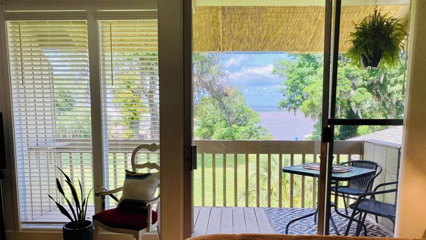 A room with a large window, a bed, a chair, and a small table. - Color Me Crazy Eclectic Studio with Bay Views! (Daphne)