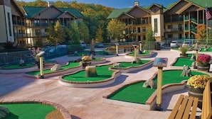 Un patio de hotel con césped verde, senderos de piedra y bancos de madera.